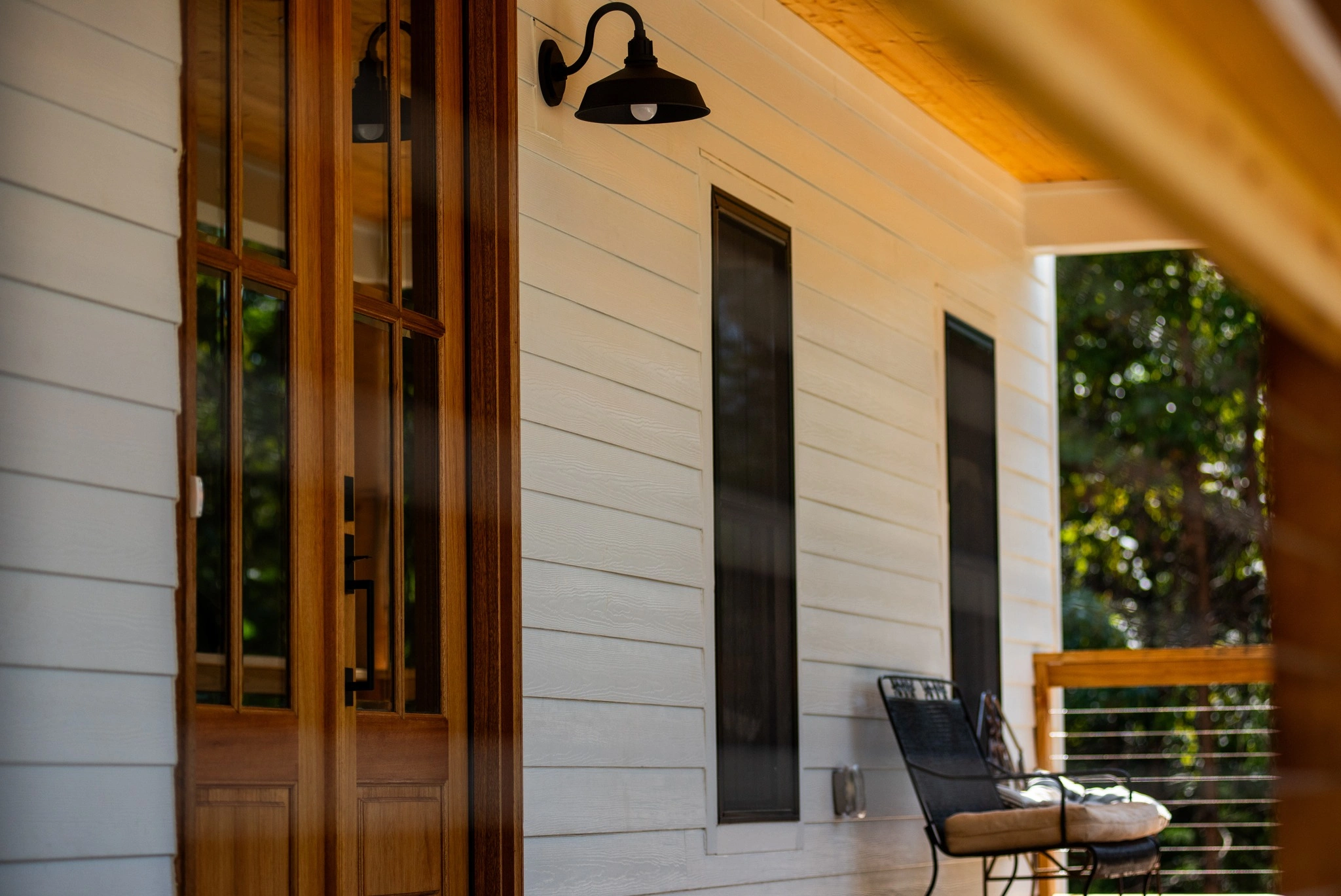 White siding and a wood door on a covered porch